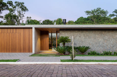 Modern single-story house with large wooden door and stone wall façade.