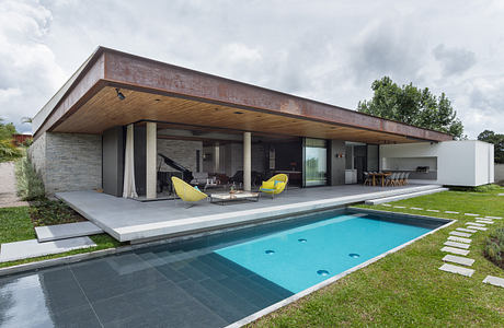 Modern home with large windows, overhanging roof, and pool.