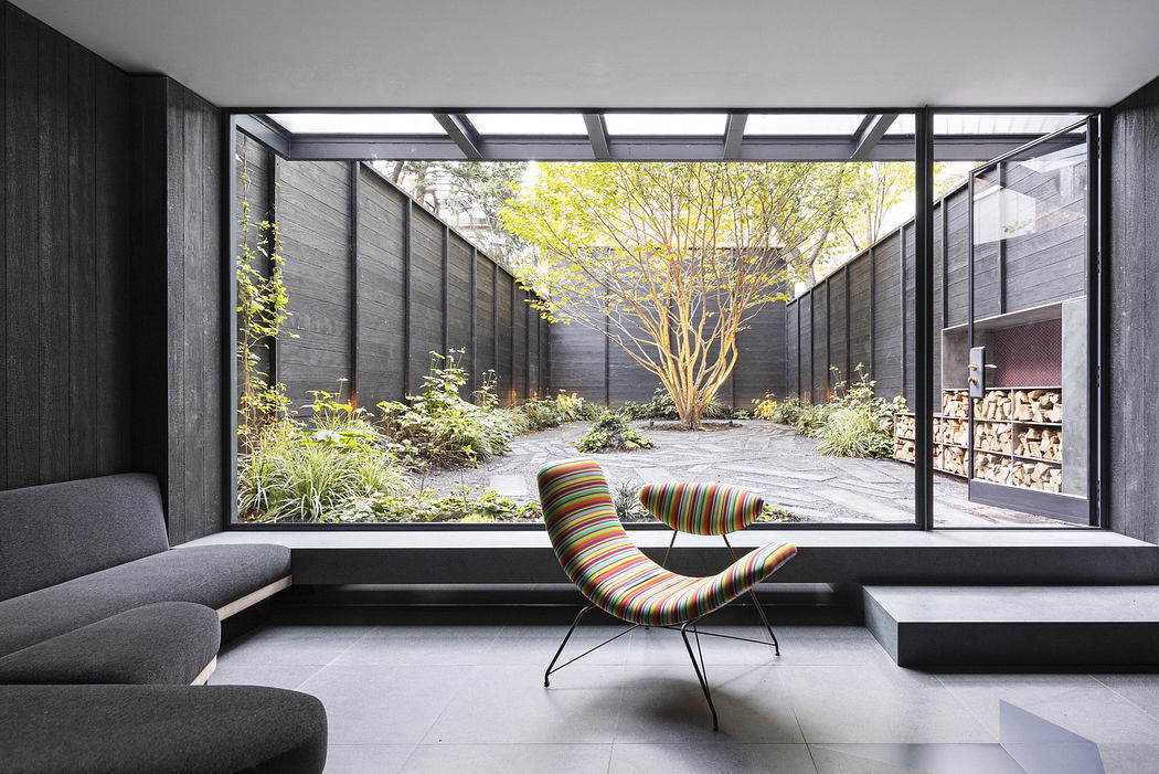 Minimalist room with large window overlooking a courtyard garden.