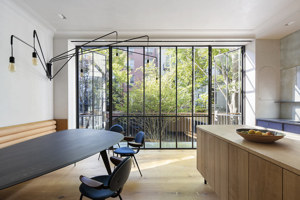 Modern dining room with large windows overlooking trees.