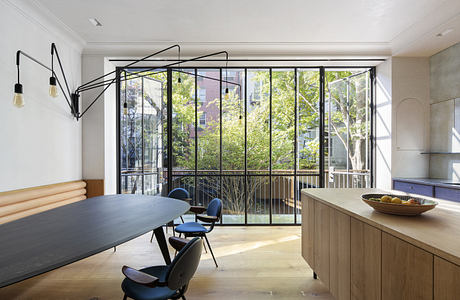 Modern dining room with large windows overlooking trees.