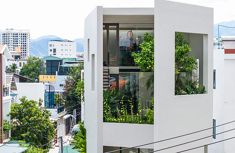 Modern urban house with green balconies and cityscape background.