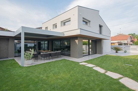 Modern two-story house with large windows and outdoor patio area.