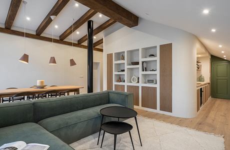 Modern living room with exposed beams, green sofa, and minimalist decor.