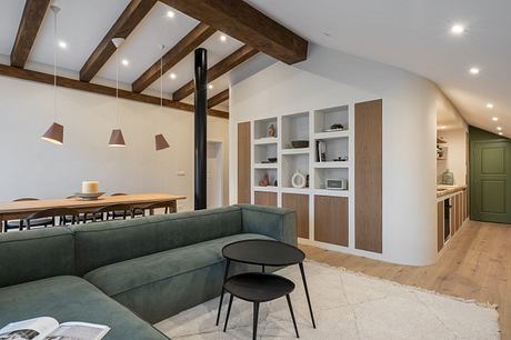 Modern living room with exposed beams, green sofa, and minimalist decor.