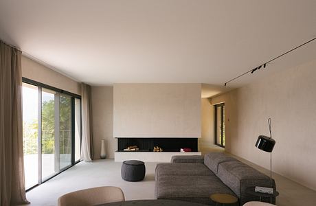 Minimalist living room with neutral tones, modern furniture, and large windows.