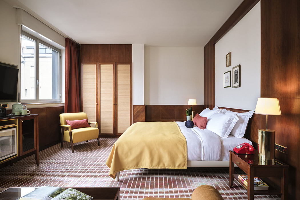 Modern hotel room interior with a neatly made bed, wooden furnishings, and warm lighting