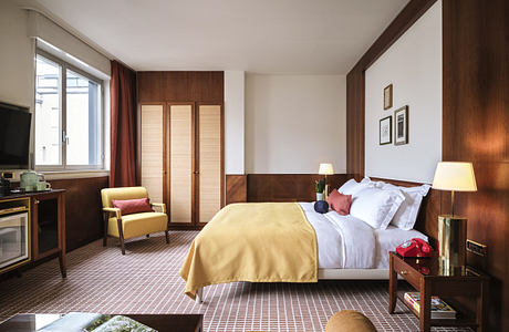 Modern hotel room interior with a neatly made bed, wooden furnishings, and warm lighting