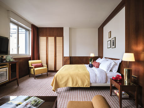 Modern hotel room interior with a neatly made bed, wooden furnishings, and warm lighting