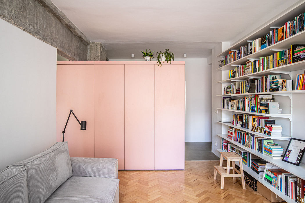 Modern living room with pink closet doors and a wall bookshelf.