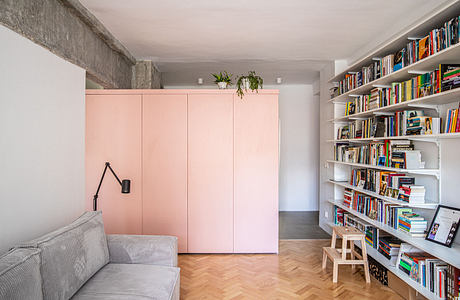 Modern living room with pink closet doors and a wall bookshelf.