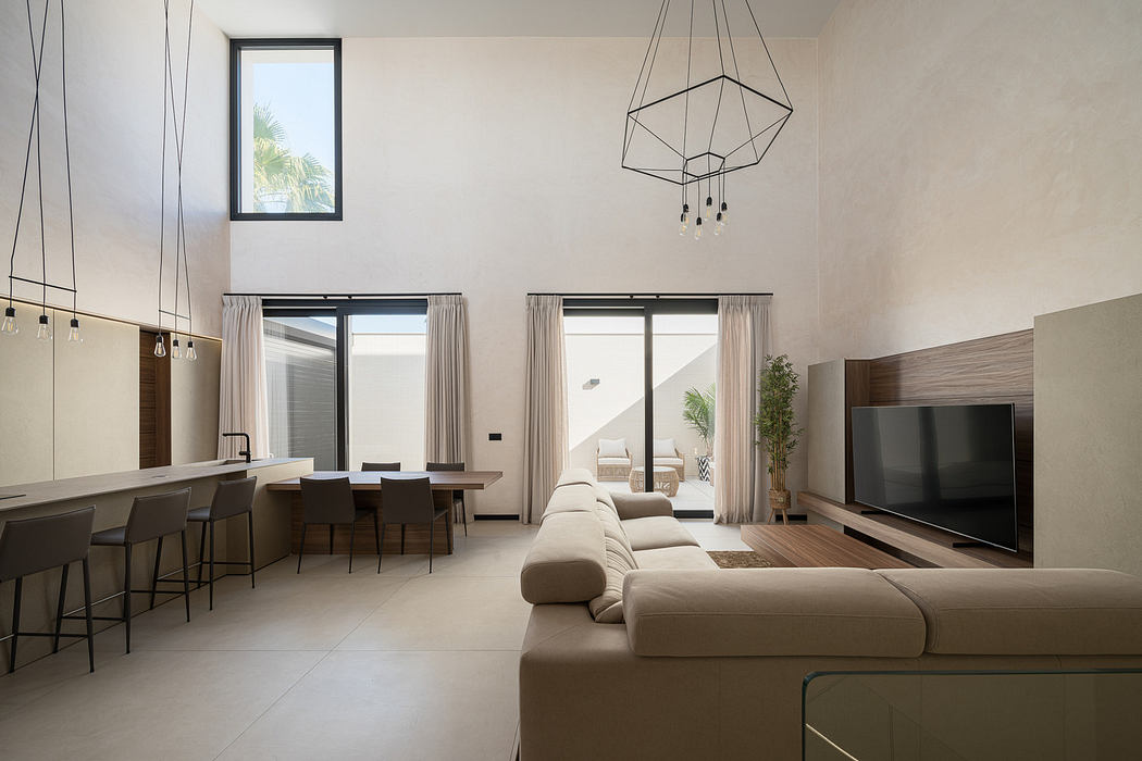 Modern living room with minimalistic decor, large sofa, and pendant lighting.