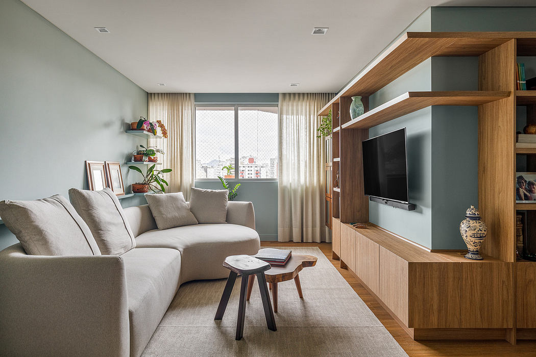 Modern living room with sectional sofa, wooden TV cabinet, and soft color palette.