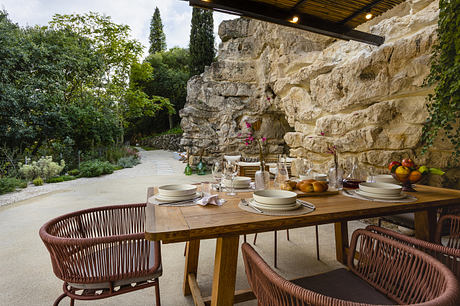 Elegant outdoor dining setup with rustic table and wicker chairs near a stone wall