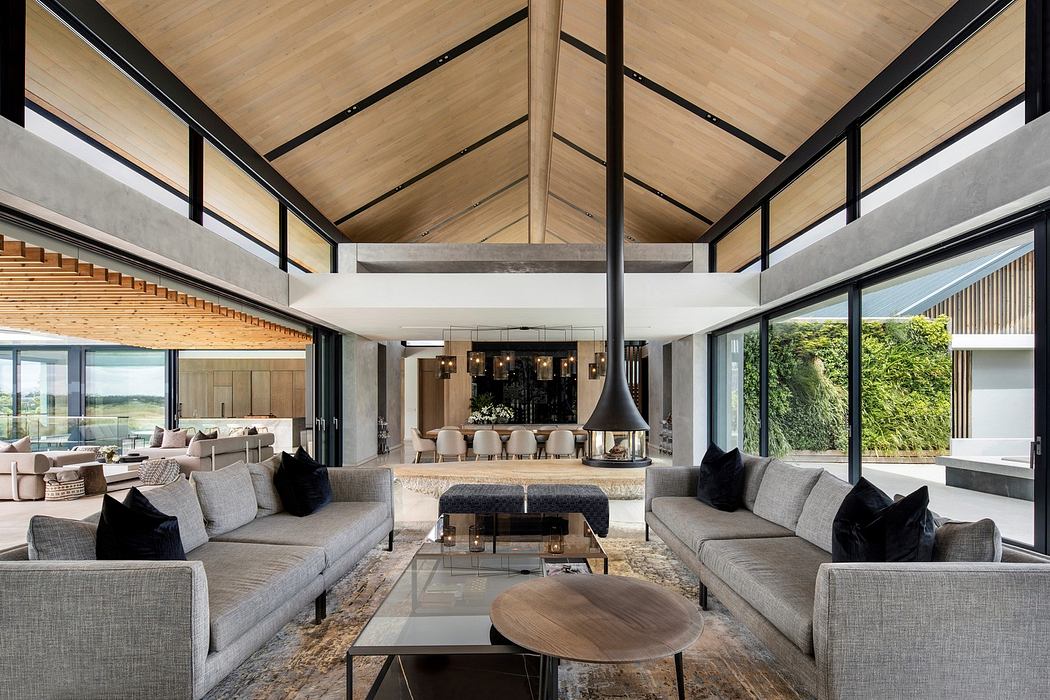 Modern living room with large windows, vaulted ceiling, and minimalist furniture.