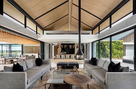 Modern living room with large windows, vaulted ceiling, and minimalist furniture.