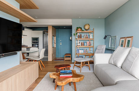 Modern living room with blue walls, wooden furniture, and an open-plan layout.