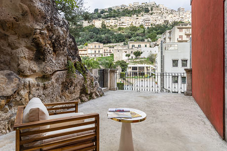 Outdoor patio with chair, table, and view of hillside buildings.