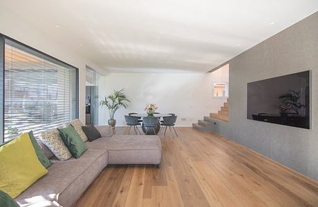 Modern living room with large sofa, wooden floors, and dining area.