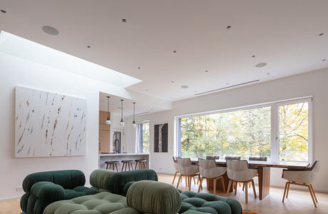 Modern living room with large windows, green sofa, and dining area.