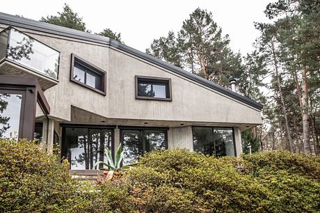 Modern house with large windows nestled in a wooded area.