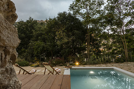 Modern outdoor pool with wooden deck and lush greenery.