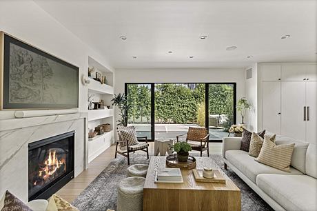 Modern living room with a fireplace, white sofa, and large windows.