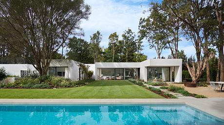 Modern house with large windows overlooking a swimming pool and garden.