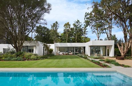 Modern house with large windows overlooking a swimming pool and garden.