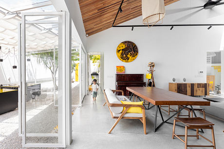 Modern dining area with open layout, wooden furniture, and white walls.