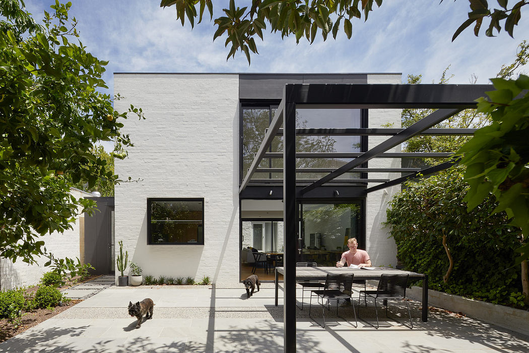 Modern backyard with a white brick house, patio furniture, and a pergola.