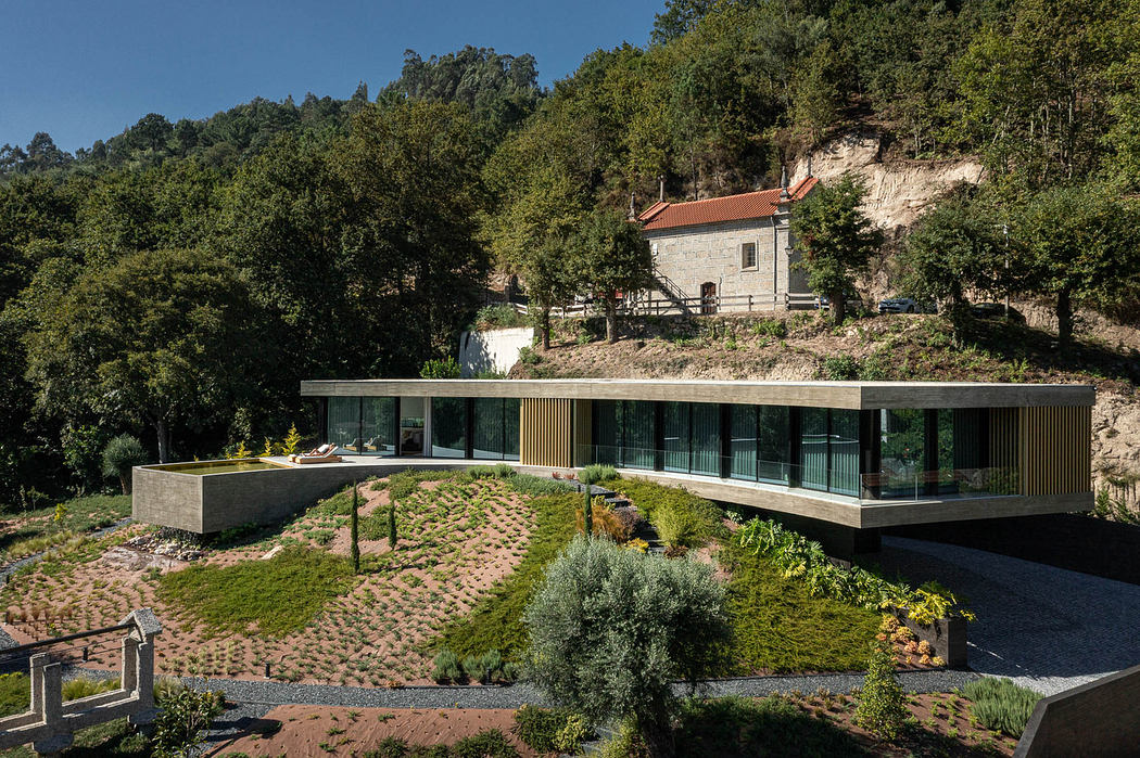 Modern hillside home with large glass facade and terraced garden.