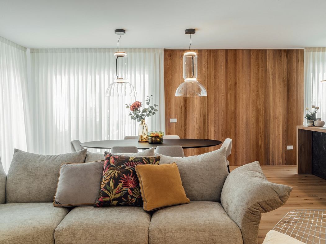 Modern living room with a beige sofa, wooden wall paneling, and pendant lights
