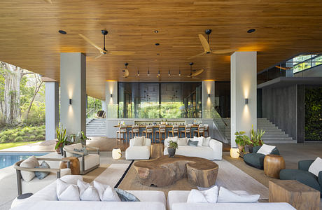 Modern open-plan living space with wooden ceiling and pool view.