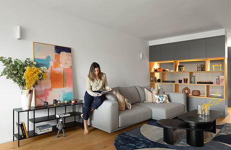 Modern living room with elegant decor and a woman reading on the sofa.