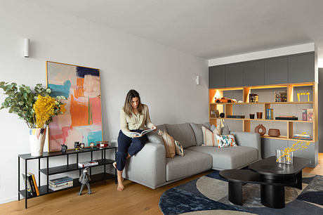 Modern living room with elegant decor and a woman reading on the sofa.