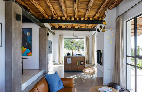 Modern room with exposed wooden beams, tan couch, and minimalistic decor.