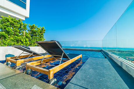 Modern rooftop terrace with loungers and sea view.