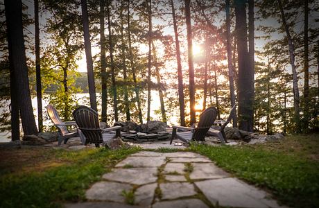 A serene lakeside seating area with Adirondack chairs at sunset.