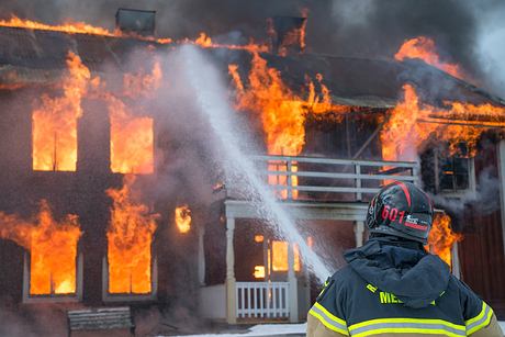 A firefighter spraying water on a burning building.