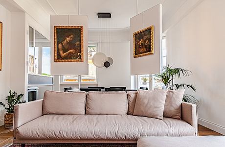 Modern living room with a beige sofa, framed artwork, and a potted plant