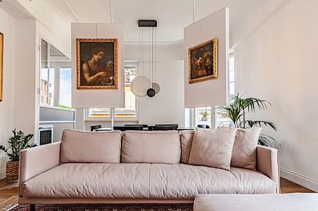 Modern living room with a beige sofa, framed artwork, and a potted plant