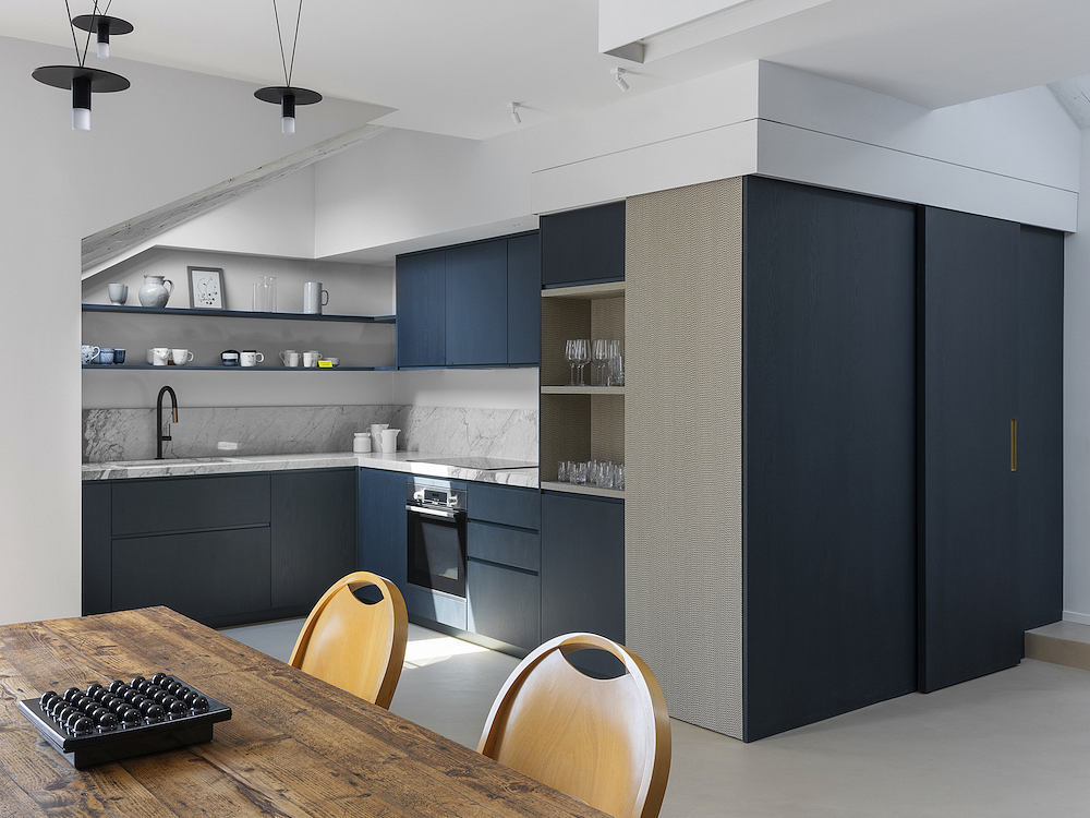 Stylish kitchen with navy cabinets and marble backsplash.