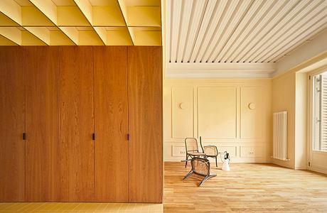 Modern room with wooden walls, herringbone floor, and a single chair.