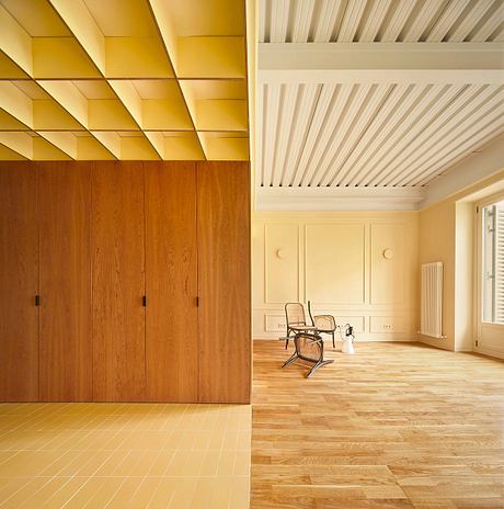 Modern room with wooden walls, herringbone floor, and a single chair.