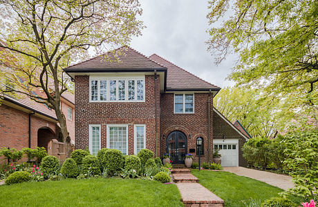 Traditional brick home with lush landscaping and a pathway.