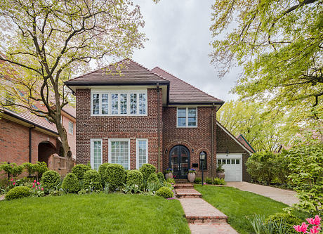 Traditional brick home with lush landscaping and a pathway.