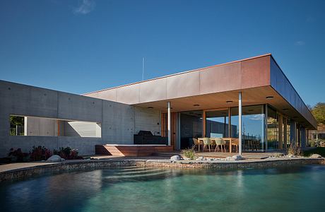 Modern house with large windows overlooking a pool.