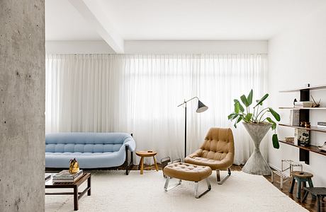 Modern living room with minimalist furniture and white curtains.