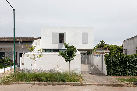 Minimalist white house with asymmetrical windows and a flat roof.